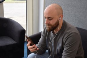 Digital USB Type-C Earphones in white. They are worn by a man who has a set plugged into his mobile phone. They are suitable to use with a range of devices. Compatible with Google & Siri voice control.