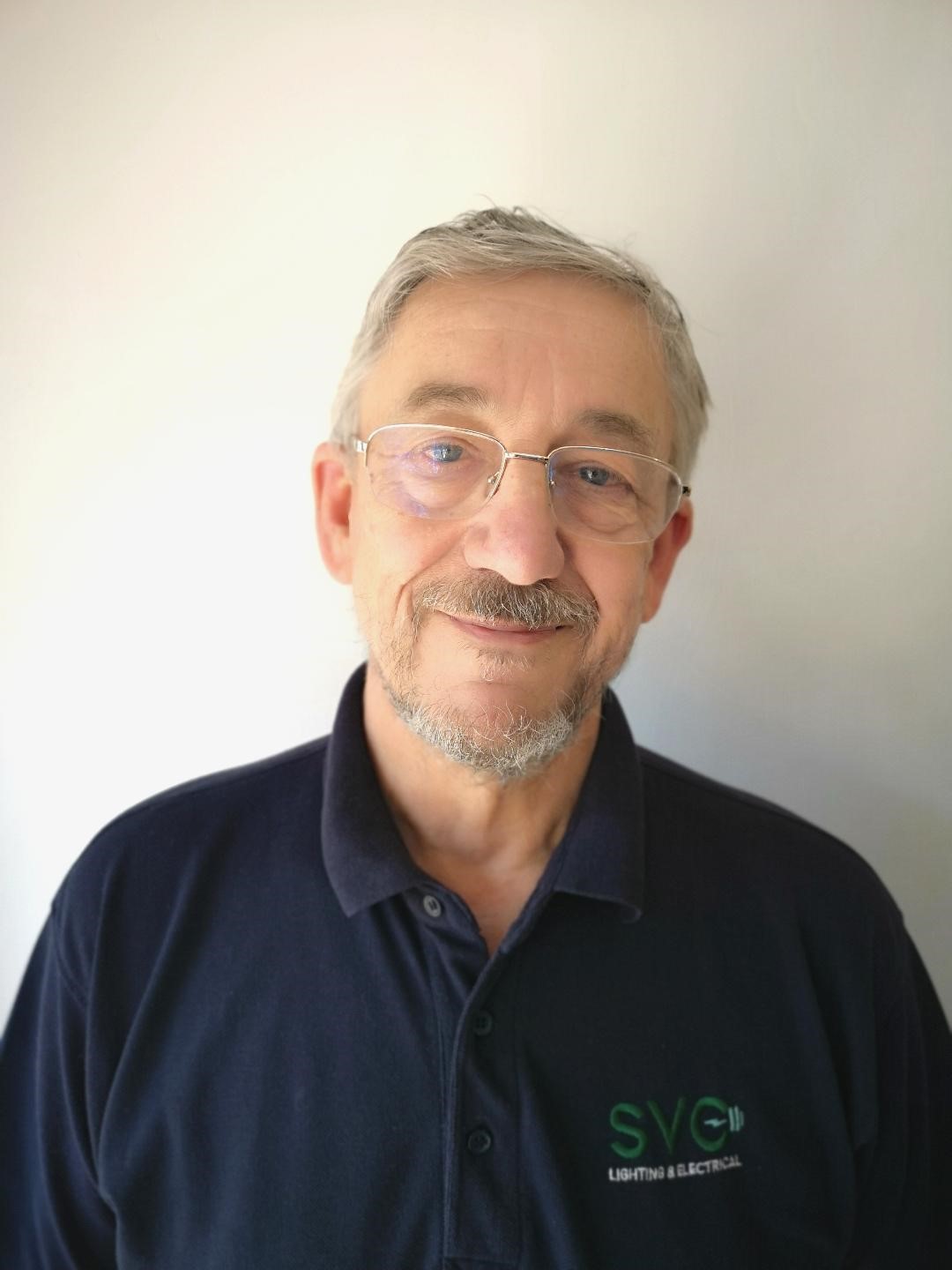 Image of man with greying hair wearing a navy polo shirt